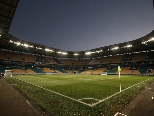 Fu&szlig;ballstadion bei D&auml;mmerung mit Flutlicht und perfekt gr&uuml;nem Rasen aus der Eckfahnen-Perspektive